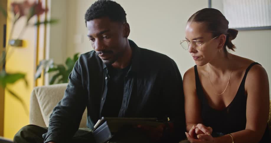 Woman and man sit together on couch viewing laptop screen