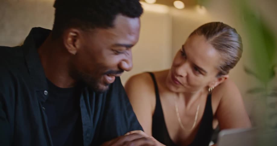 A couple laugh while looking at a laptop together