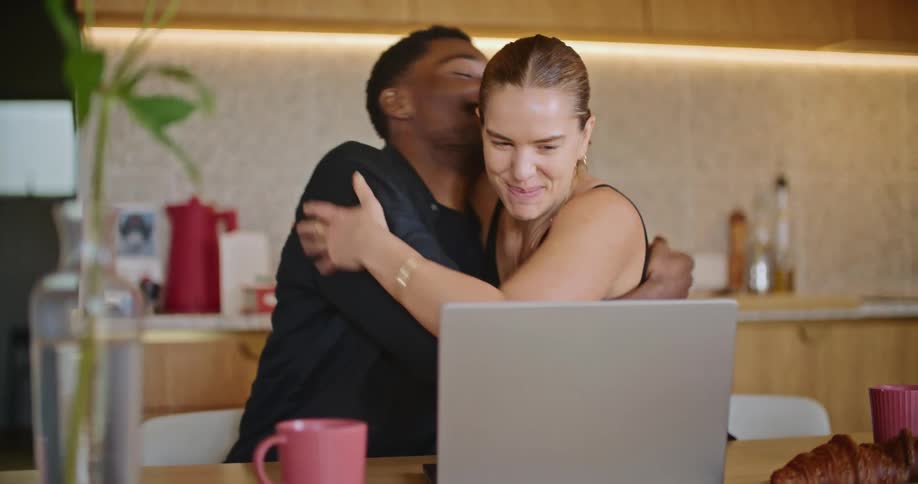 Man and woman smile and hug after looking at laptop contents
