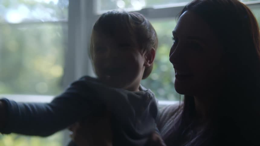 A woman smiles as she acts silly along with the young boy shes holding