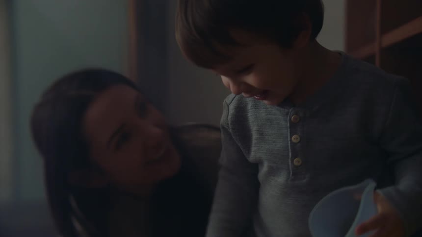 A little boy taking a cup off a shelf and shaking it up and down with cards in it then kneeling down to pick up more cards his mother points out