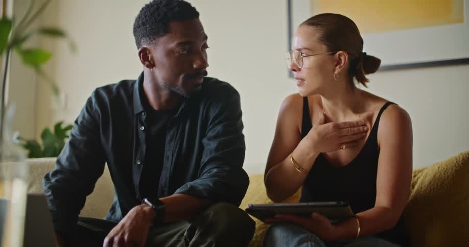 A man and woman sit together on a couch while having a conversation