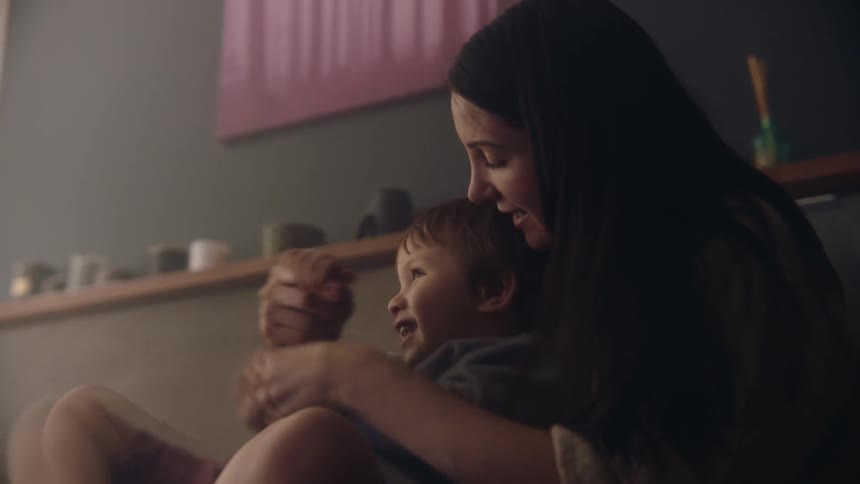 Woman holds her baby on her lap as they play with their arms together