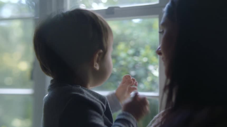 A woman holds a young boy who is excited to look out of a window