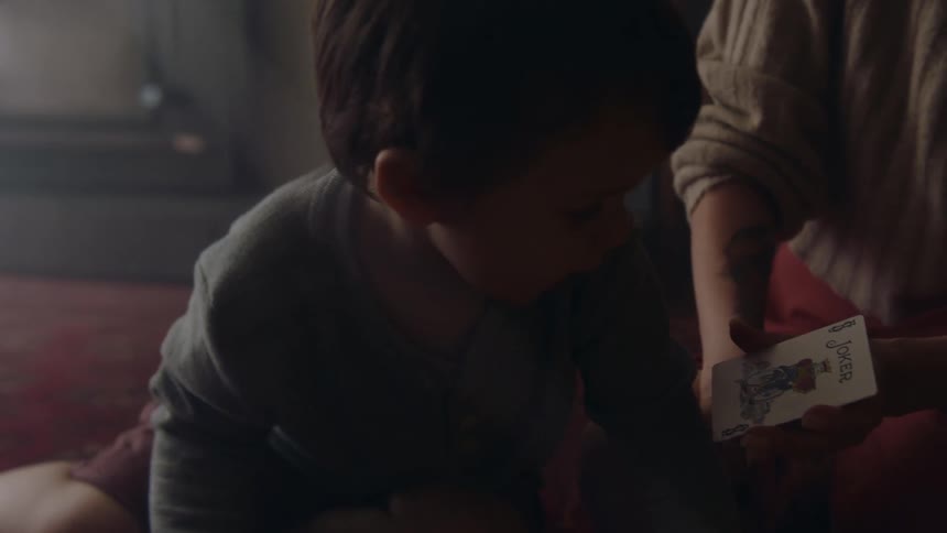 A boy holds up a playing card