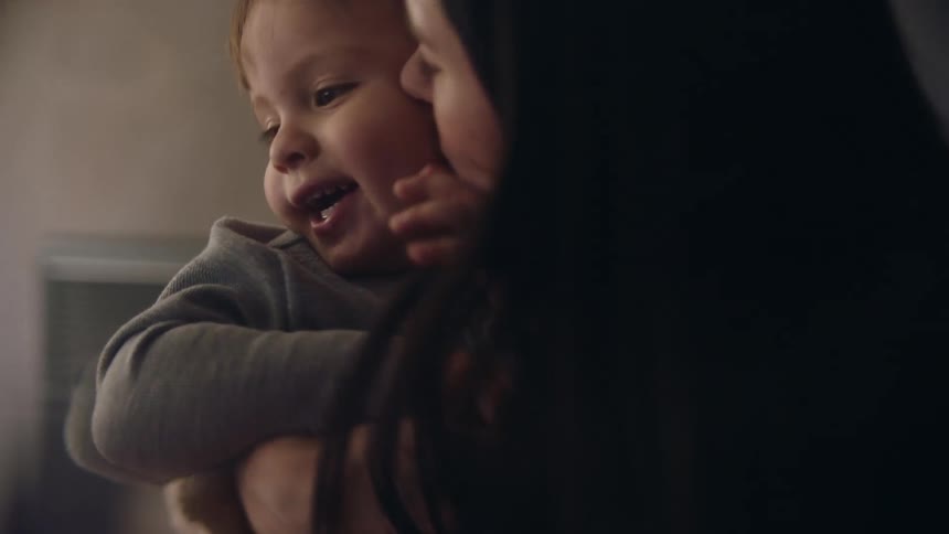 A close up of a mother and son sitting together while the mother kisses the sons cheek