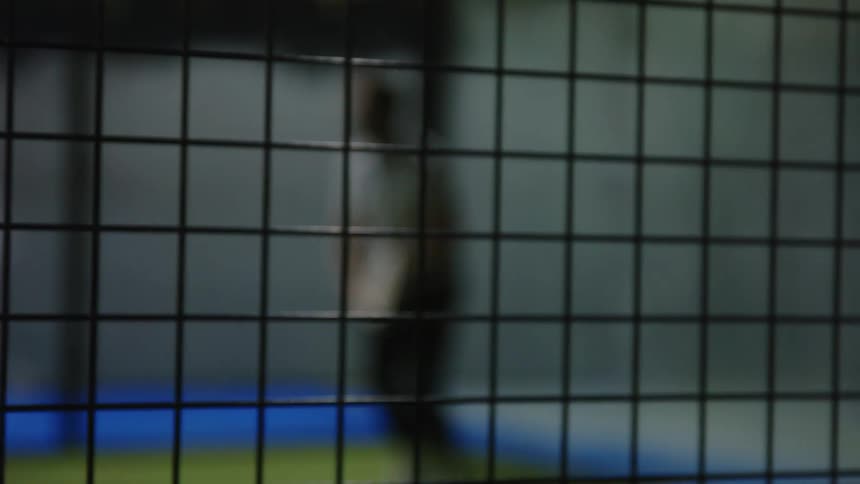 Young active man playing squash on an indoors court at night