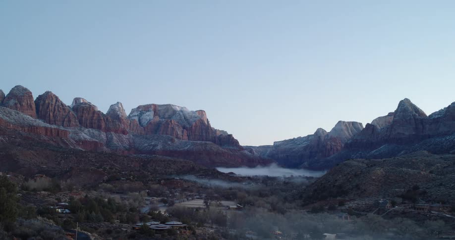 Time lapse of a small town in a valley between desert rock formations at dawn