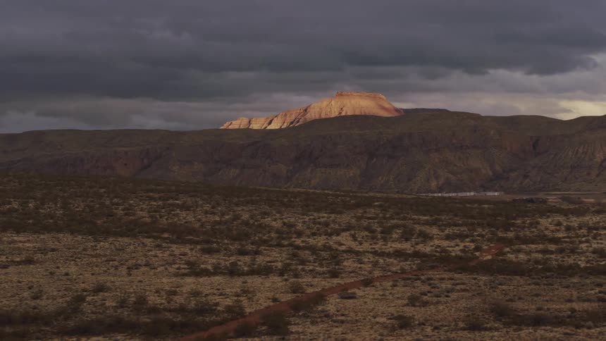 Aerial view of a distant mesa illuminated by the last bit of sunlight on a stormy evening