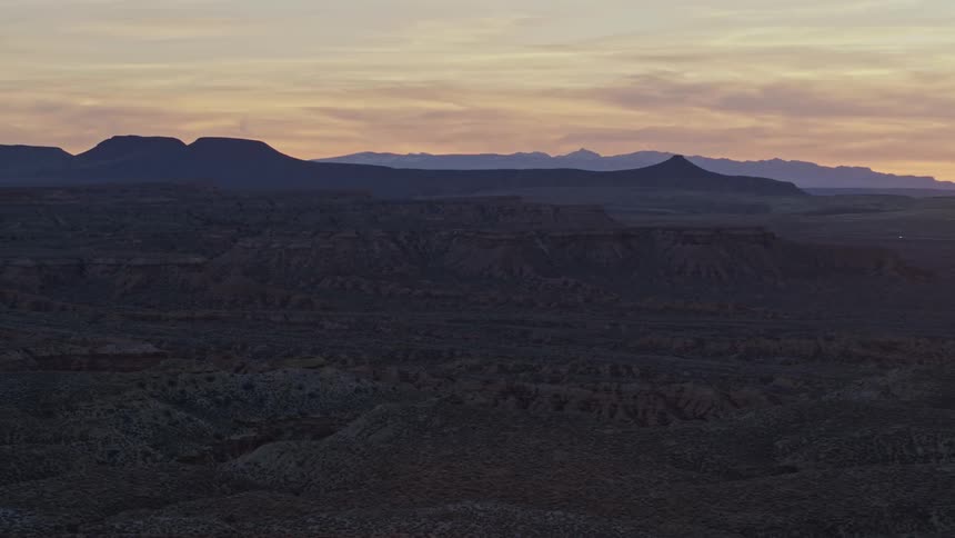 Aerial orbiting view of mesas and mountains in the desert badlands in the evening