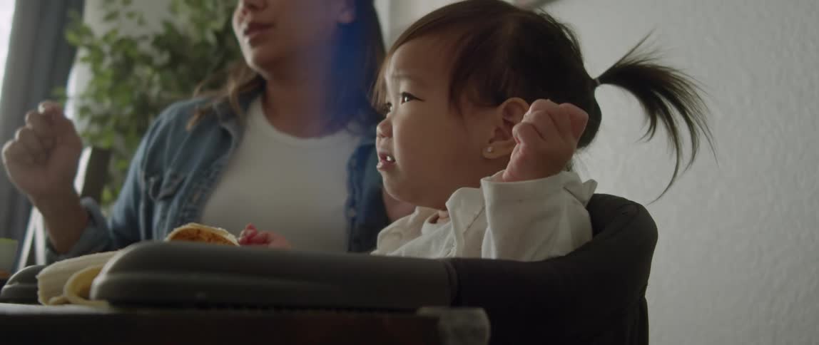 Close up of a baby girl sitting in the couch at home next to her mother