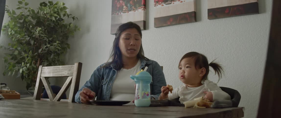Pregnant mother sitting next to eating toddler gets up to leave table