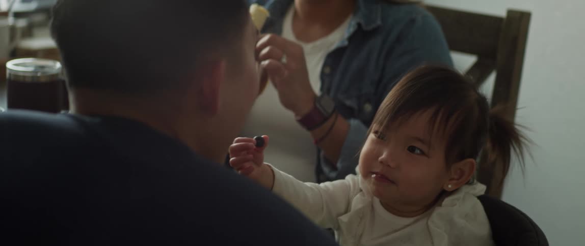 A little girl feeds her father a blueberry but then eats it herself instead