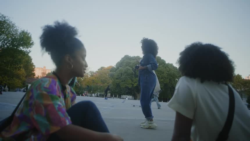 Two young women looking a friend dance in the park at morning