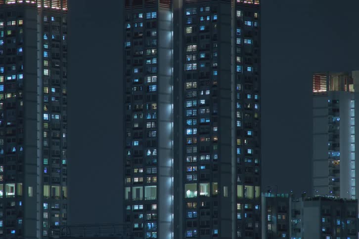 The window lights of tall buildings in a city turn off at night through a time lapse view