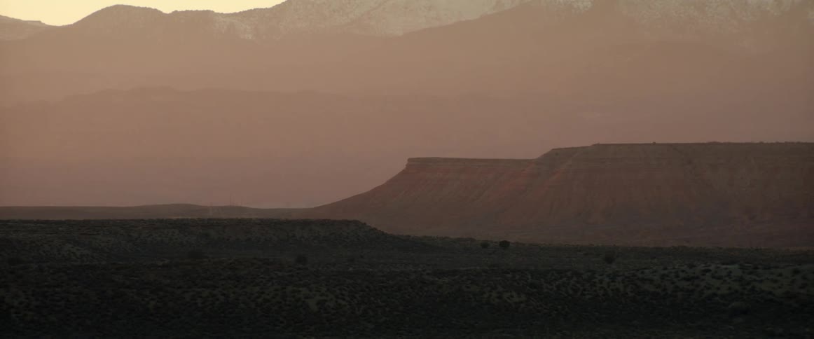 Panoramic view of distant silhouetted mountain ranges in the desert in the evening haze