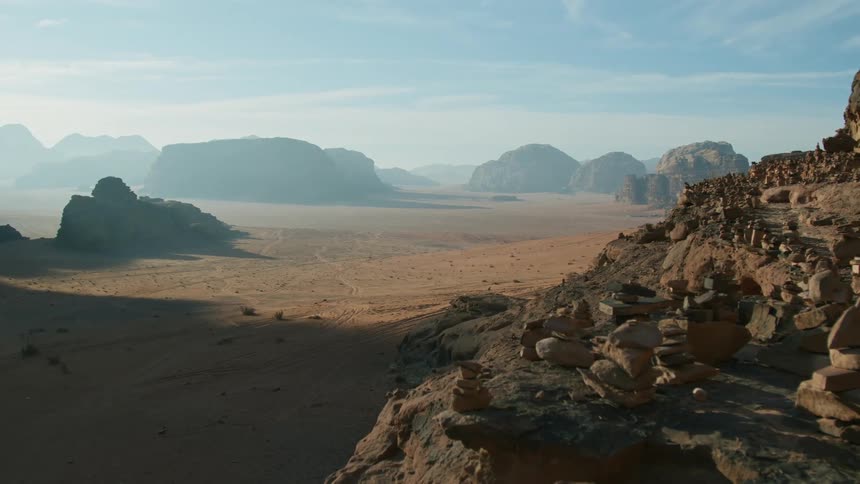 Balancing rock piles sculptures on the slopes of a mountain looking at the desert in the morning