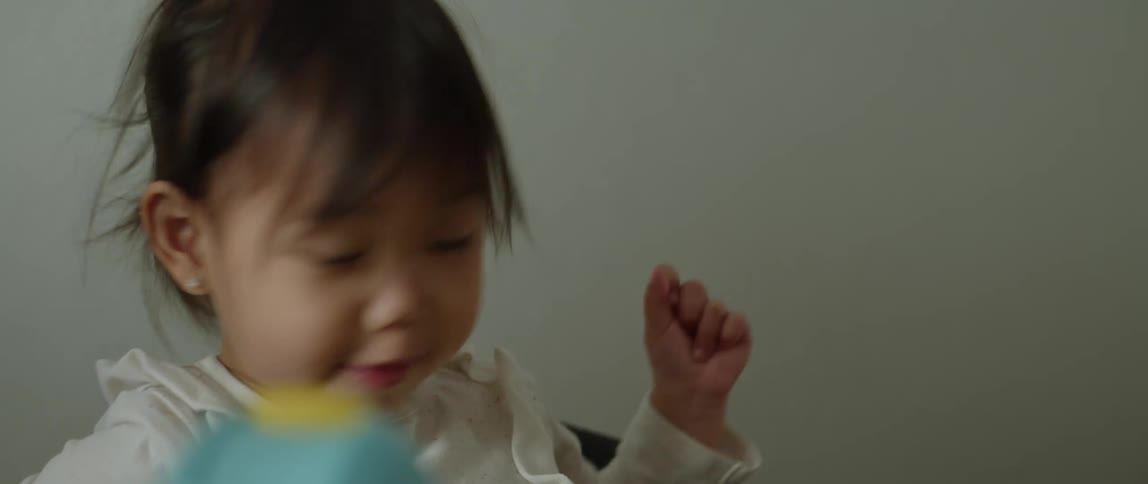 Close up of a baby sitting in the dining room at home eating food
