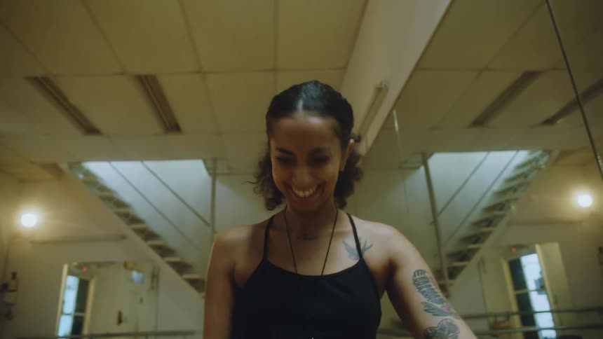 Close up of a young tattooed woman laughing while nodding inside a large room