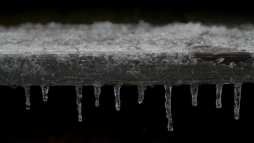 Melt water drips off of icicles on icy winter day