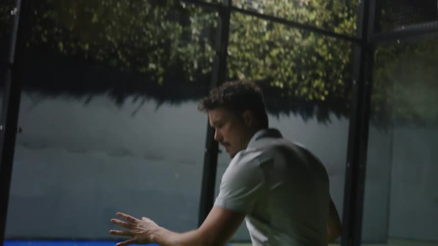 A man backs up before hitting a ball with his pickle ball paddle
