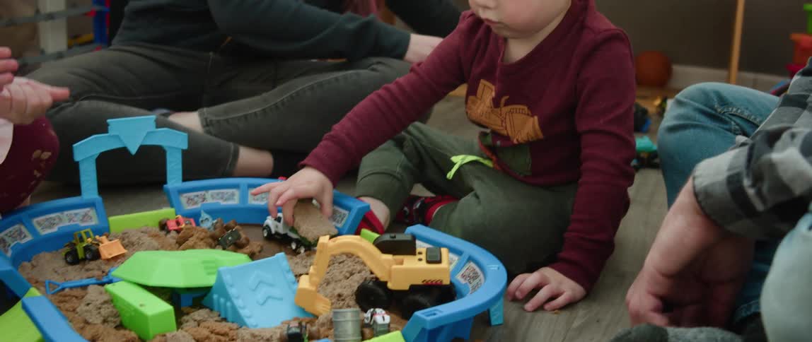 Family is hanging out together and kid is playing with its toys