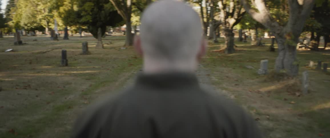 Man walks down a path in a cemetery