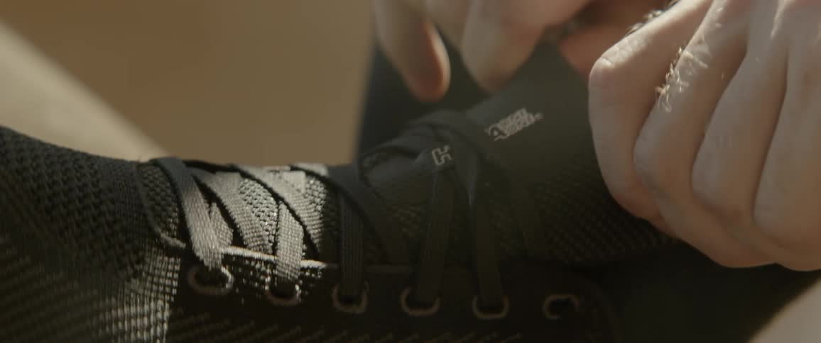 A person adjusts the black sneaker
