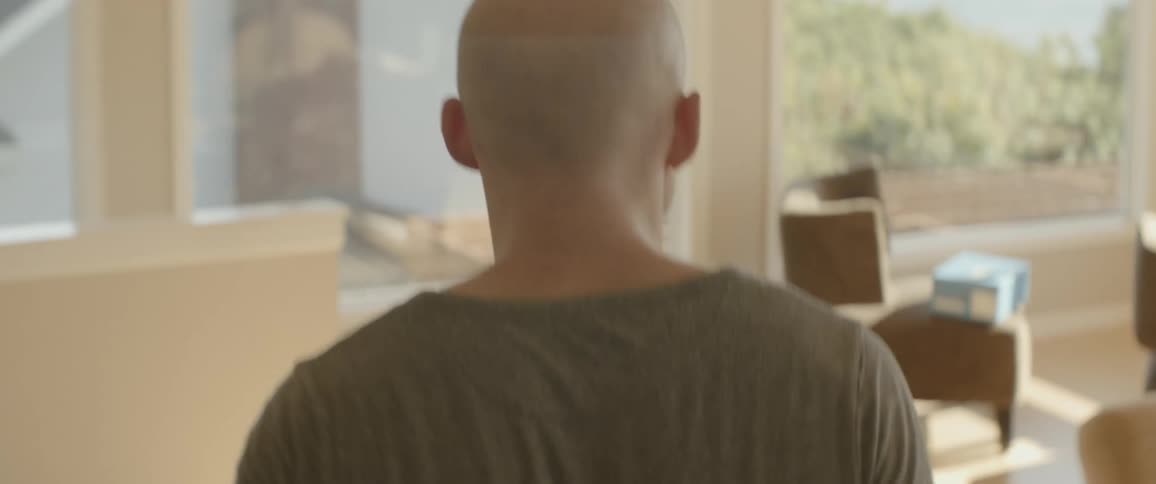 A man walks by furniture in a sunroom