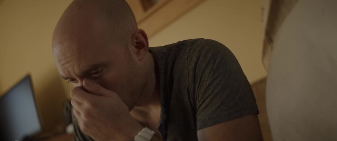 A man takes the phone away from his face and covers his face in despair