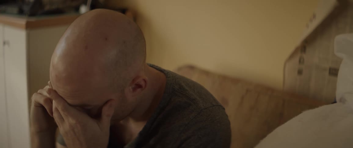 Man strokes his face while talking on phone on couch