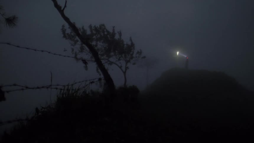 Person walking with flashlight on windy and foggy night