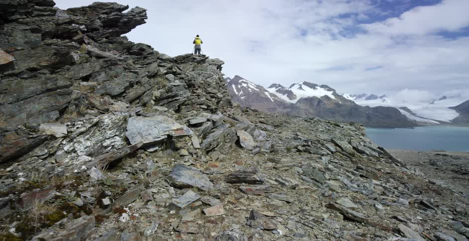 A man stands on a rocky hill