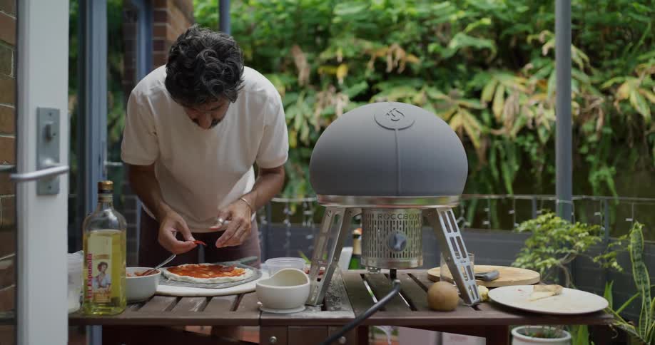 A young man is grilling food outdoors in the day time