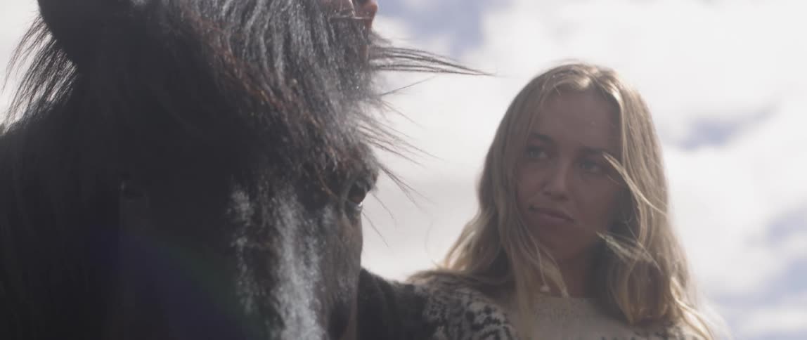 A woman pets a horse outside