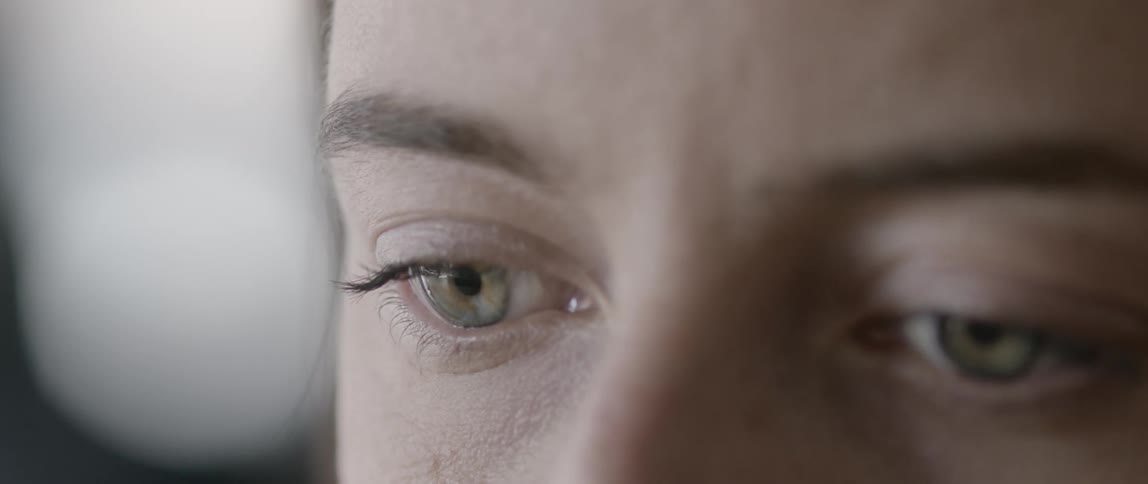 A pair of green eyes blink in daylight