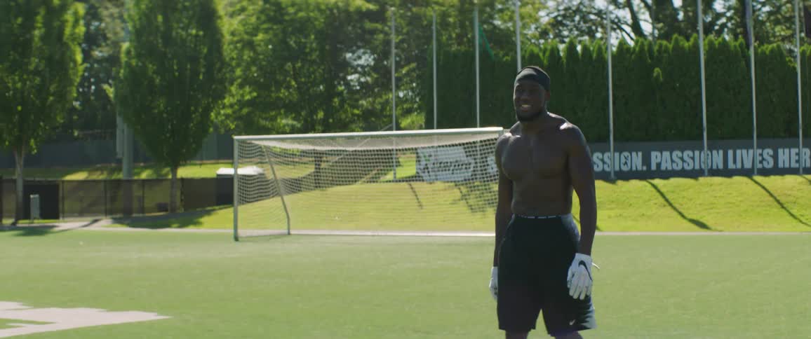Two men practice football in a large field