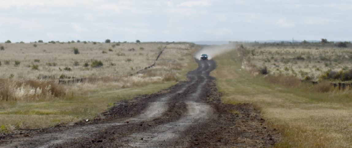 A car is driving on a road in the countryside