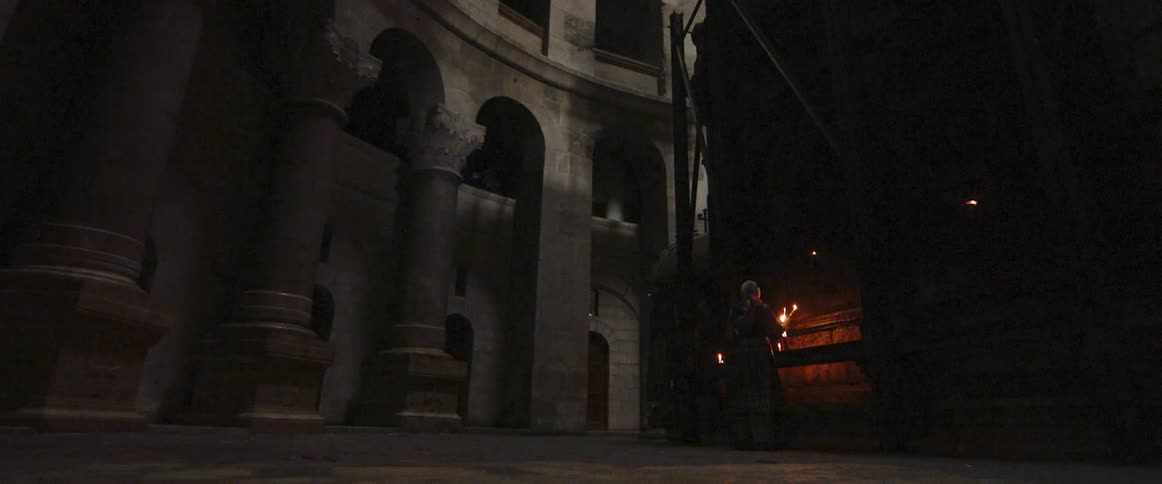 A person holds a burning torch in a stone building