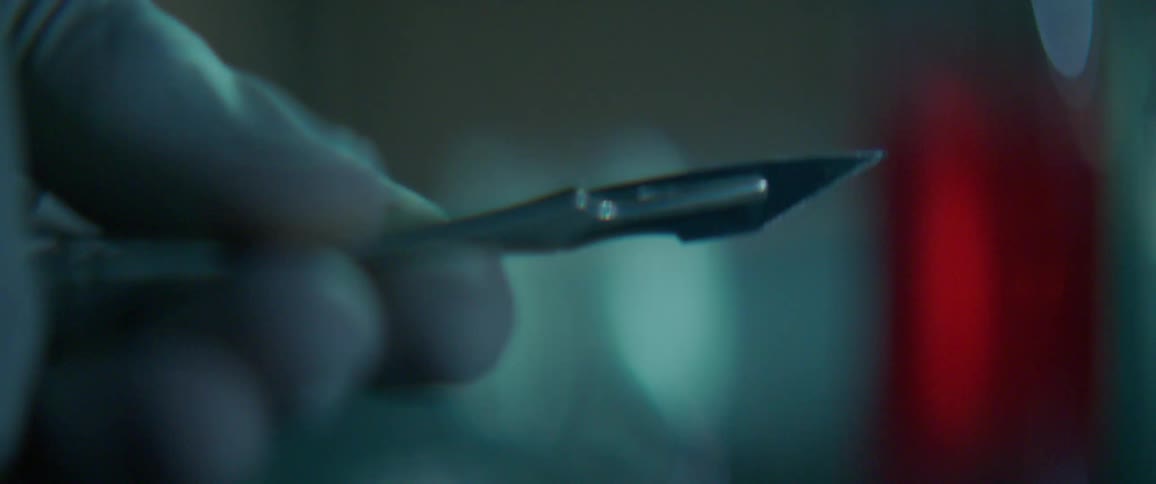 Fingers twirl a shiny sharp scalpel