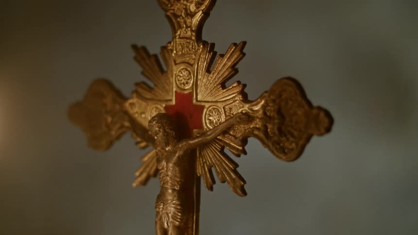 Flickering light illuminates a metal crucifix