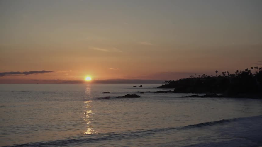 The sun is setting as birds fly over the shore