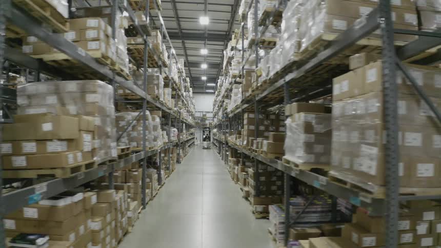A large storage warehouse with boxes on the shelves and people in the aisles