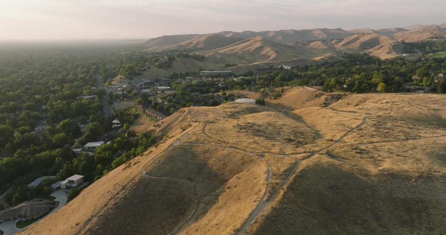 An aerial of a mountainous region with houses near the mountains in a rural area