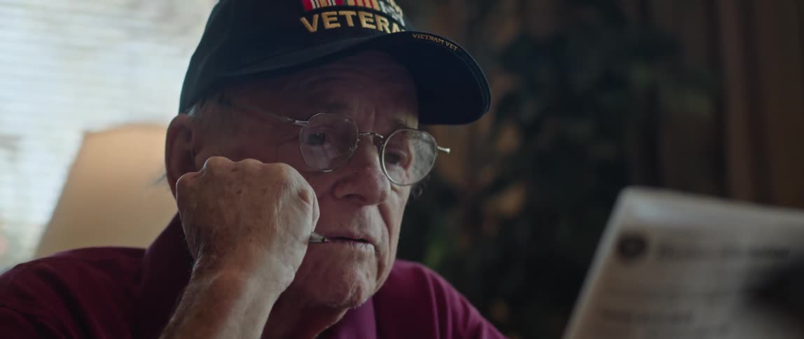 An elderly man reads a newspaper