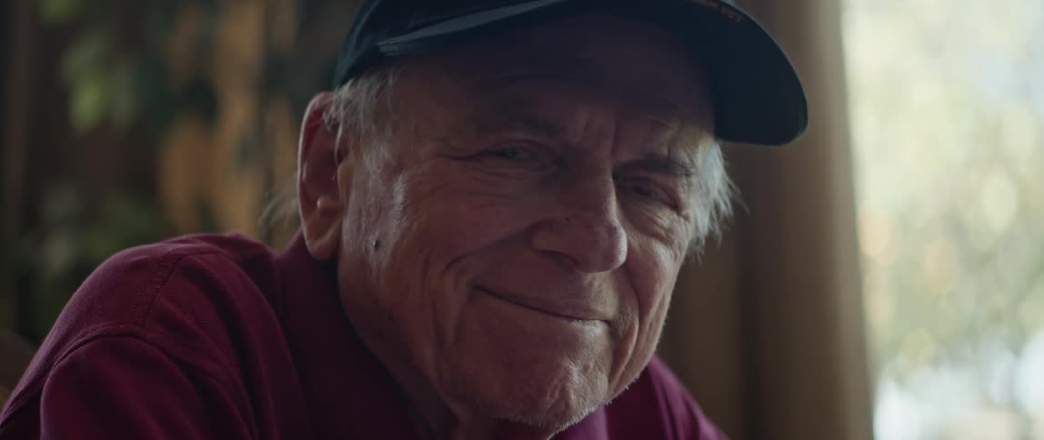 Elderly man turns from window and smiles