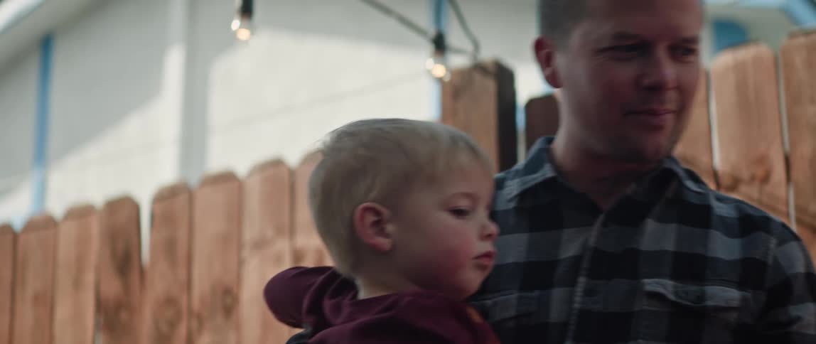 A father holding his son outside then setting him down to walk on his own