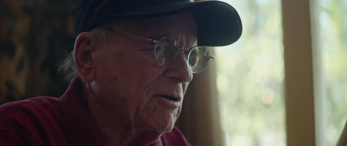 An elderly man at home talks