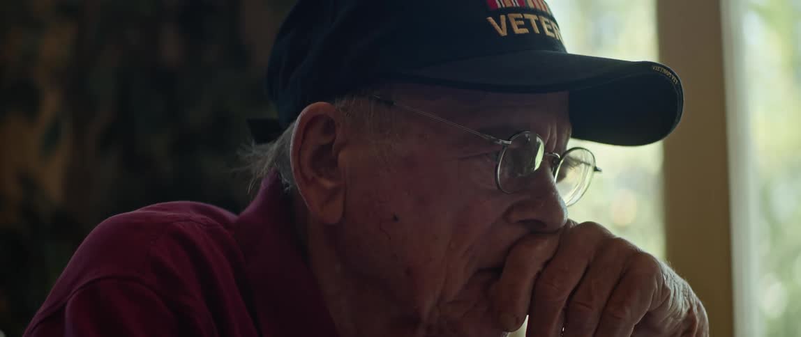 An elderly man sits and concentrates while reading a document