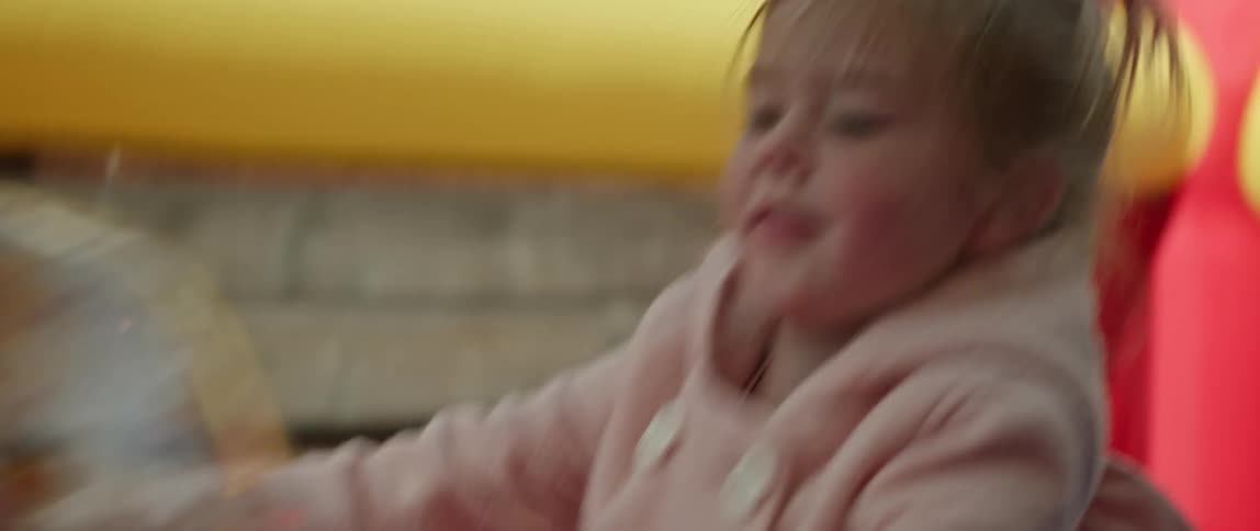 Siblings play with inflated clear ball in inflated play area